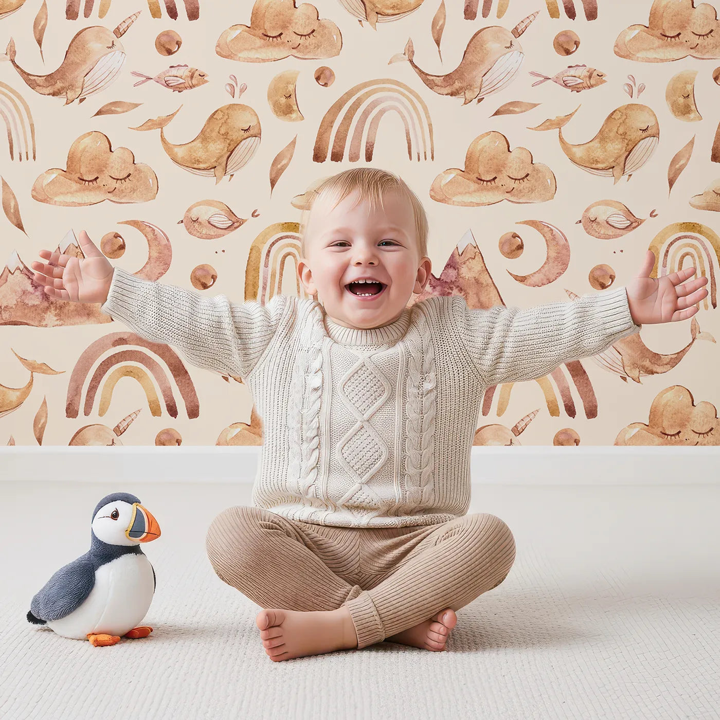 Lovely child standing in front of Whimsy Tots Whimsical Earth Friends Wallpaper in Cream with whale, dolphin, narwhal, bird, fish, rainbow, moon, mountain, cloud in design.