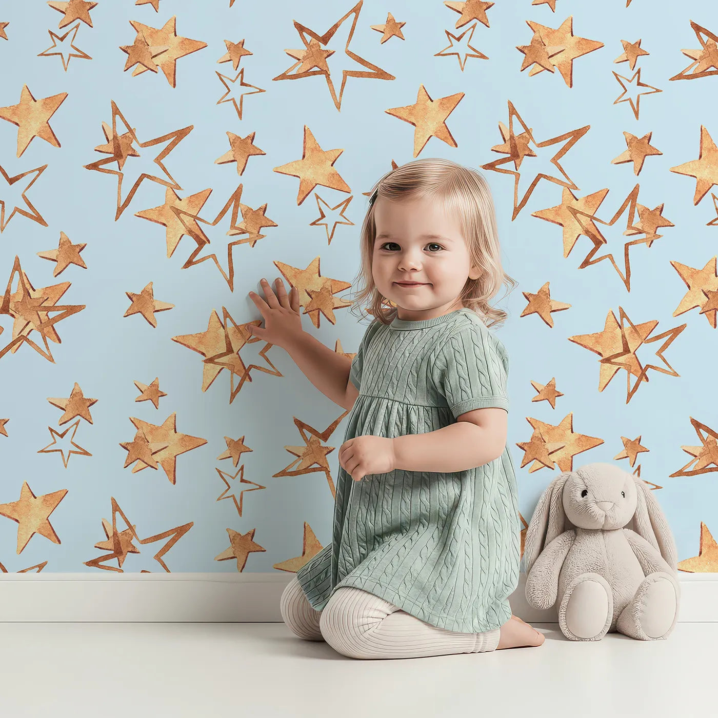 Lovely child standing in front of Whimsy Tots Golden Star Scatter Wallpaper in Sky Blue with star in design.