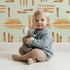 Lovely child standing in front of Whimsy Tots Painted Rhythm Wallpaper in Mint Green with line, brushstroke in design. Lovely child standing in front of Whimsy Tots Painted Rhythm Wallpaper in Mint Green with line, brushstroke in design.