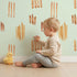 Lovely child standing in front of Whimsy Tots Painted Simplicity Wallpaper in Mint Green with line, brushstroke in design. Lovely child standing in front of Whimsy Tots Painted Simplicity Wallpaper in Mint Green with line, brushstroke in design.