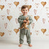 Lovely child standing in front of Whimsy Tots Heartfelt Balloons Wallpaper in White with heart, balloon, outline in design. Lovely child standing in front of Whimsy Tots Heartfelt Balloons Wallpaper in White with heart, balloon, outline in design.