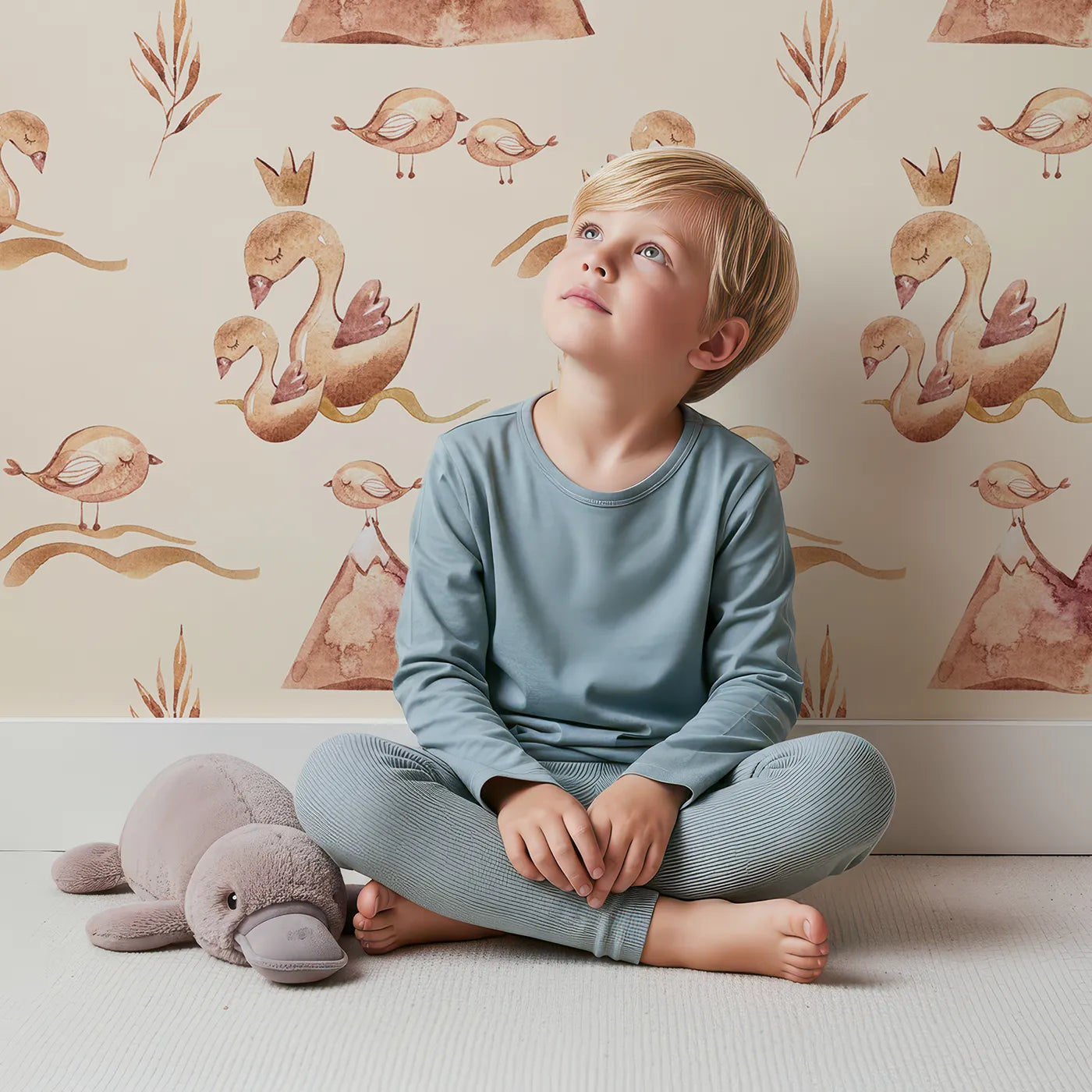 Lovely child standing in front of Whimsy Tots Feathered Serenity Wallpaper in Cream with bird, swan, crown, mountain, wing in design.