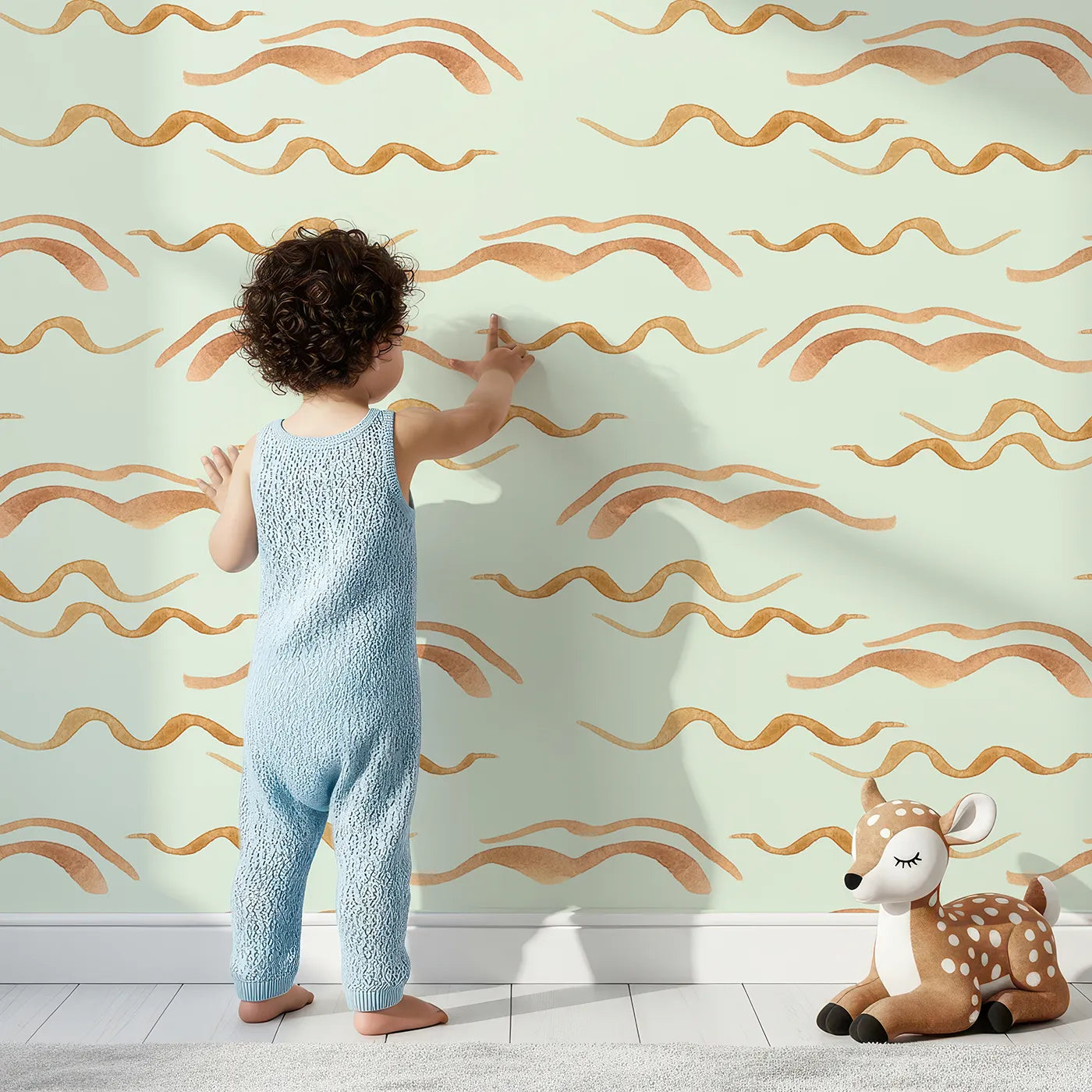 Lovely child standing in front of Whimsy Tots Soft Wave Rhythm Wallpaper in Mint Green with wave, curve, line, brushstroke, abstract in design.