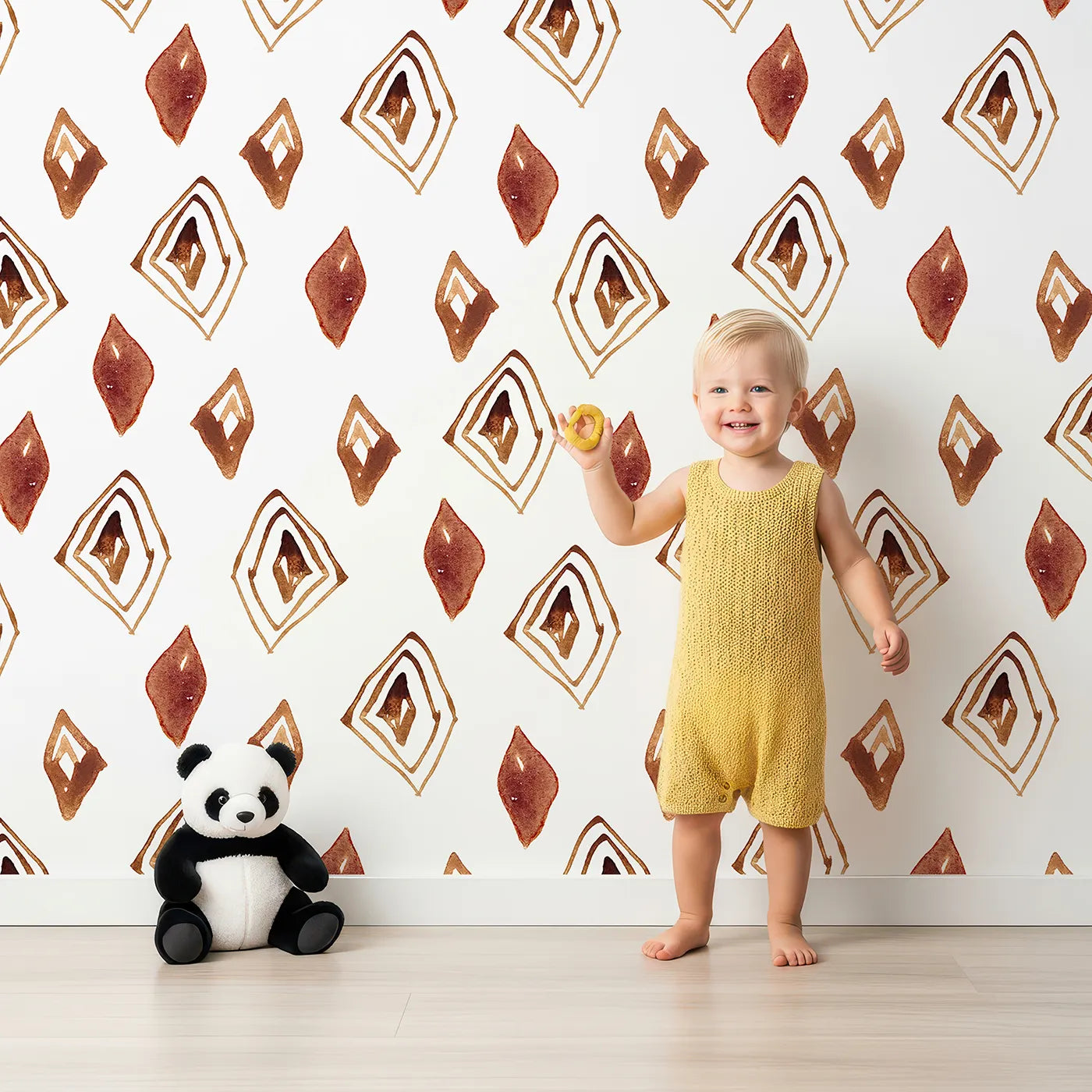 Lovely child standing in front of Whimsy Tots Terracotta Diamond Dance Wallpaper in White with diamond, shape, rust, abstract, terracotta in design.