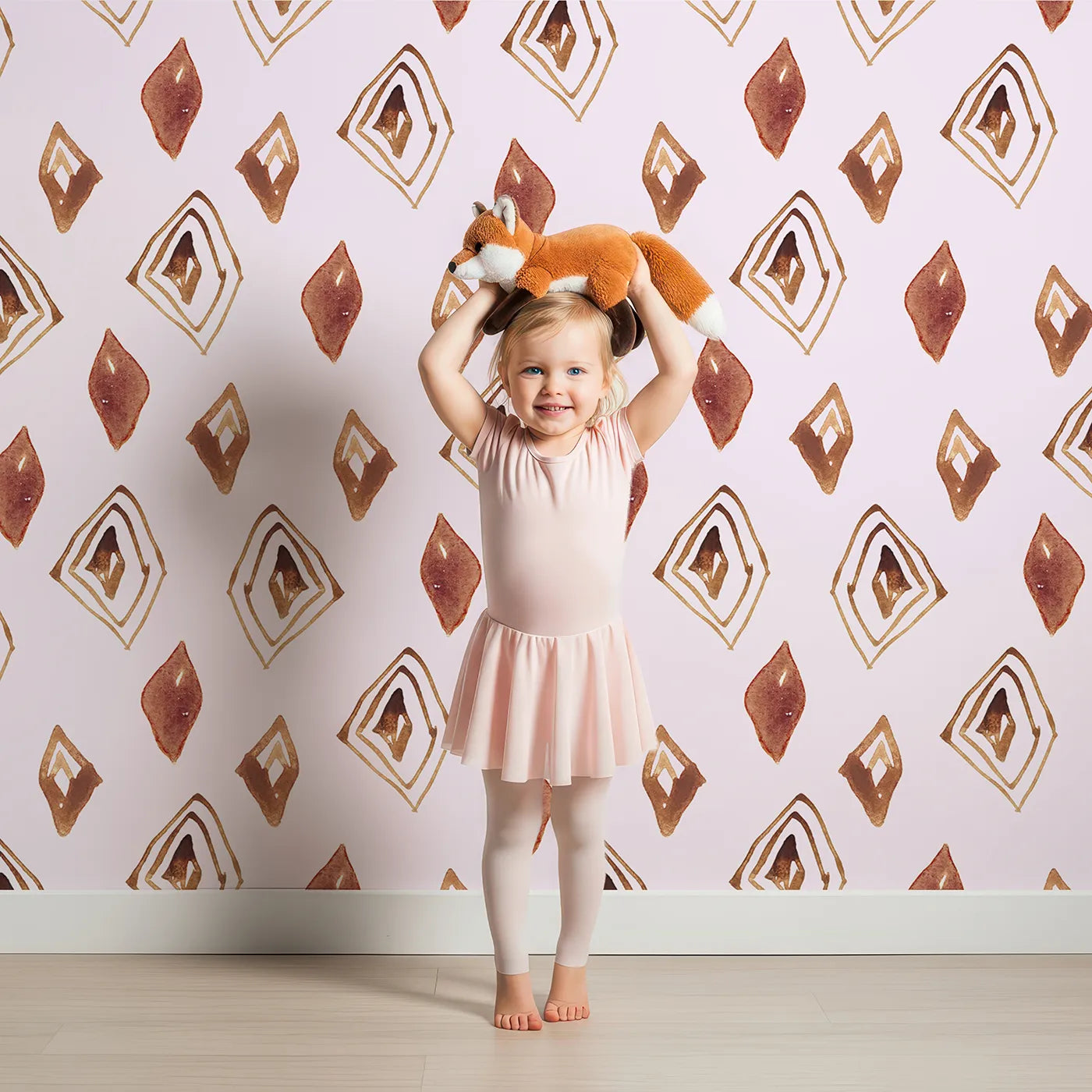 Lovely child standing in front of Whimsy Tots Terracotta Diamond Dance Wallpaper in Blush Pink with diamond, shape, rust, abstract, terracotta in design.