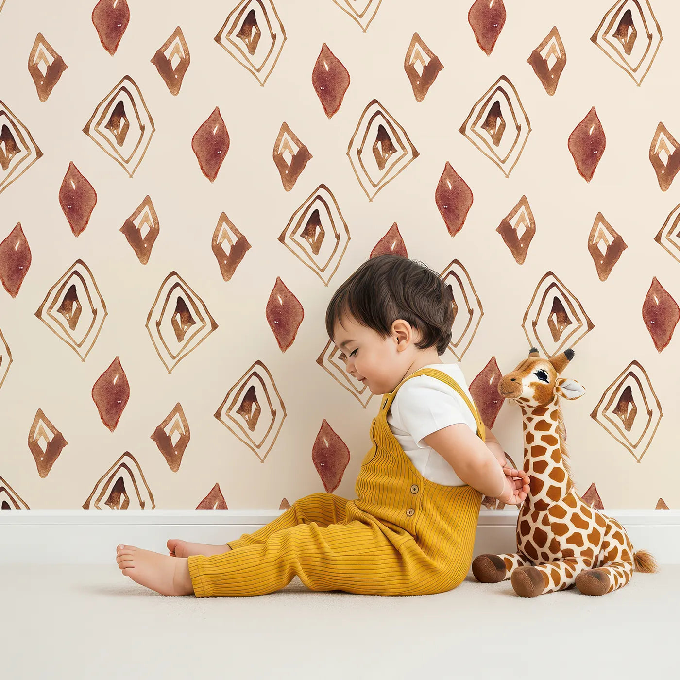 Lovely child standing in front of Whimsy Tots Terracotta Diamond Dance Wallpaper in Sand with diamond, shape, rust, abstract, terracotta in design.