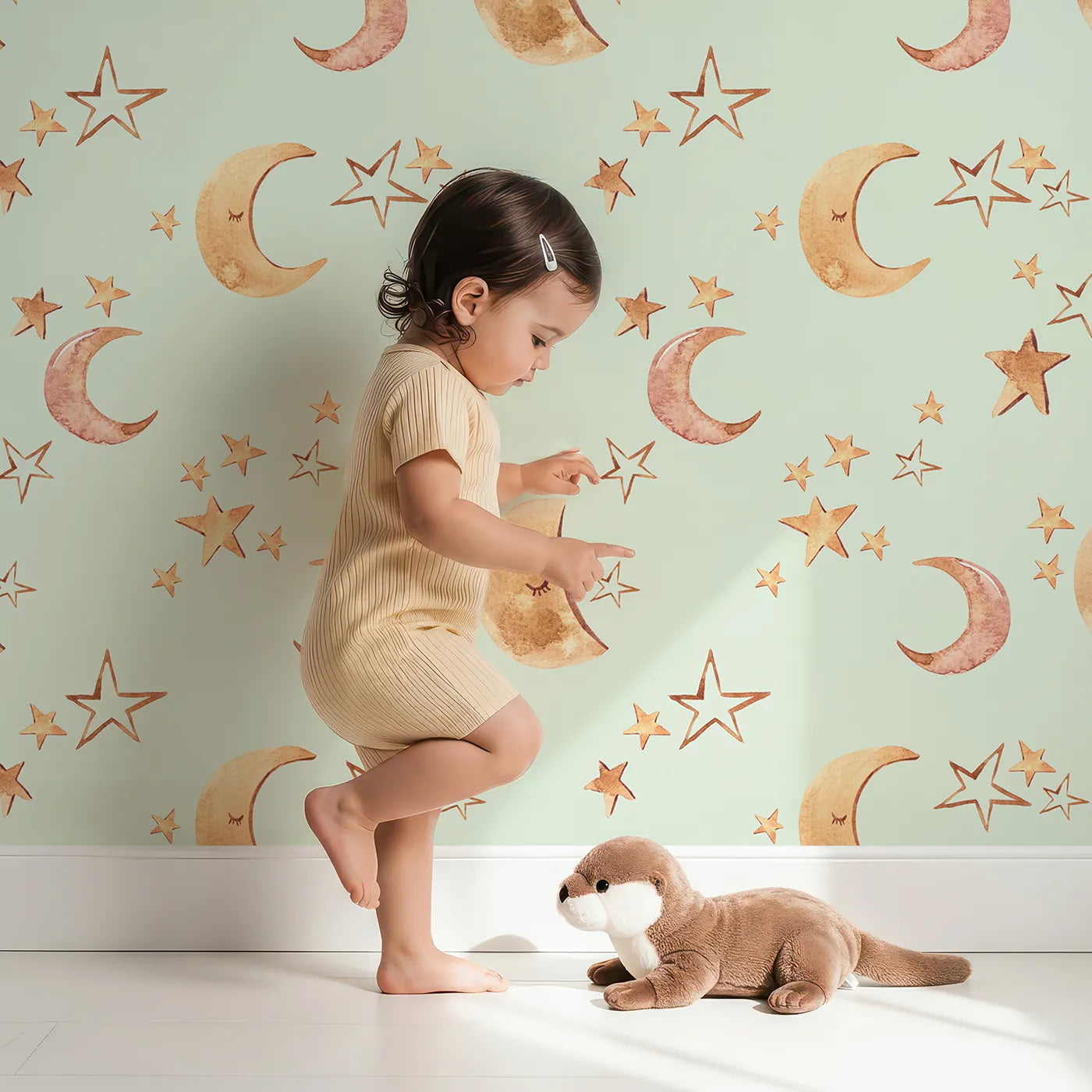 Lovely child standing in front of Whimsy Tots Sleepy Skies Shine Wallpaper in Mint Green with moon, star, sky, sleepy face in design.