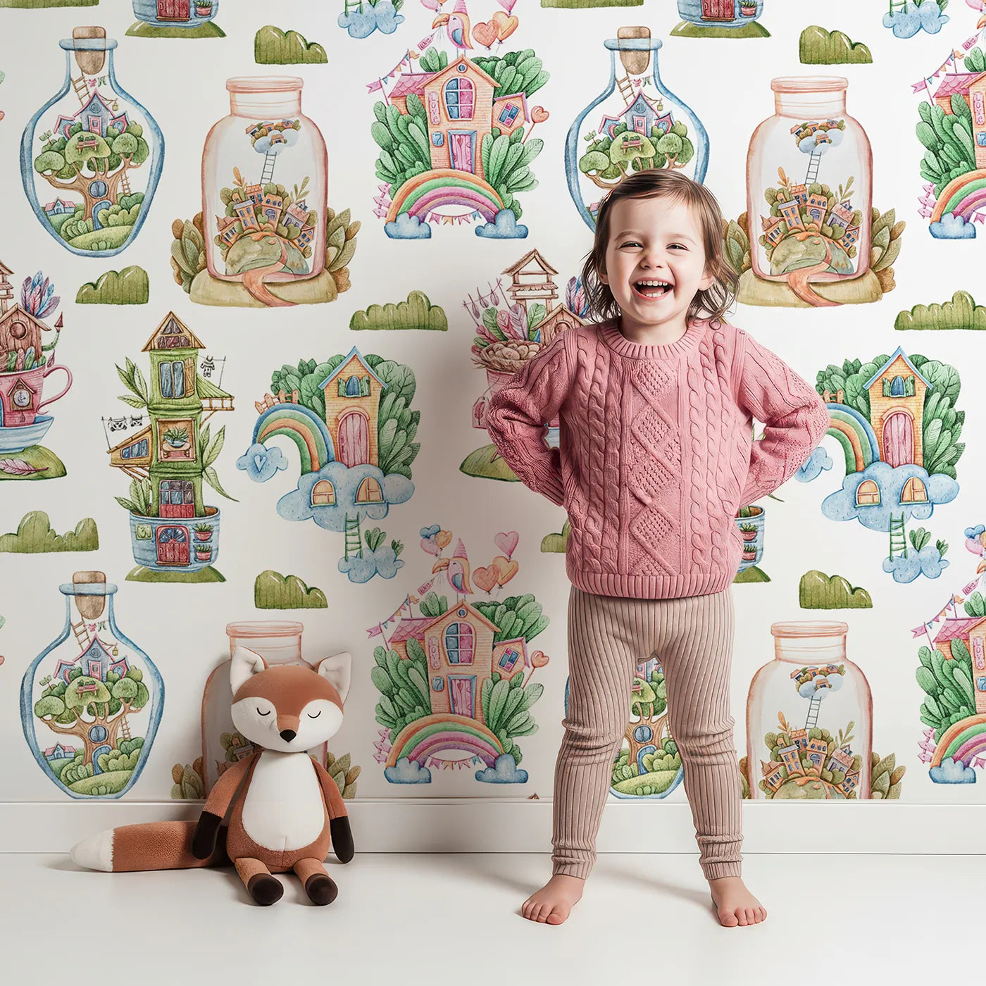 Lovely child standing in front of Whimsy Tots Whimsy Village Dreams Wallpaper in White with house, rainbow, cup, jar, cloud, heart, balloon in design.