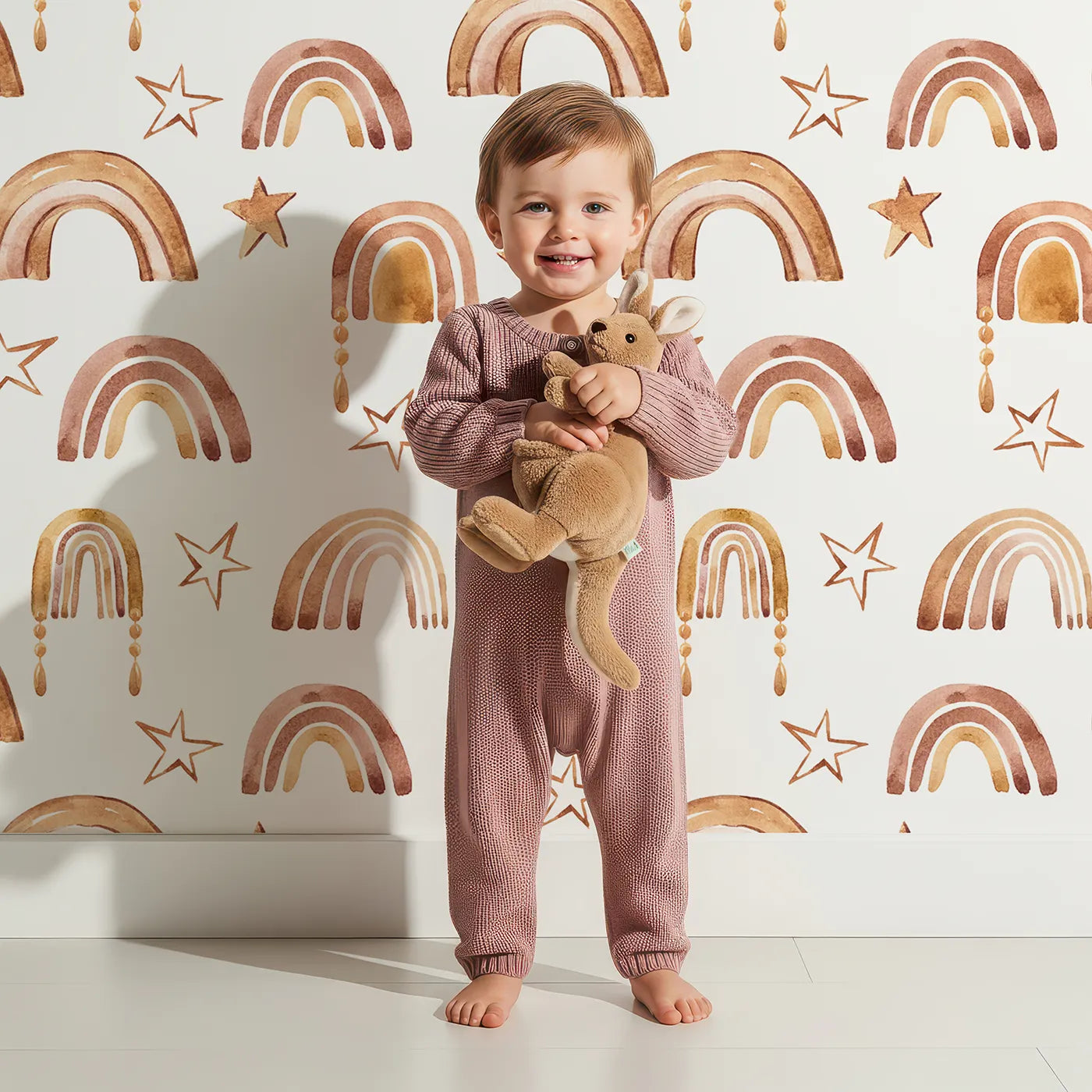 Lovely child standing in front of Whimsy Tots Golden Boho Rainbows Wallpaper in White with rainbow, star in design.