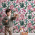 Lovely child standing in front of Whimsy Tots Enchanted Meadow Prance Wallpaper in White with unicorn, flower, leaf, tulip in design. Lovely child standing in front of Whimsy Tots Enchanted Meadow Prance Wallpaper in White with unicorn, flower, leaf, tulip in design.