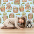 Lovely child standing in front of Whimsy Tots Secret Garden Cutaway Homes Wallpaper in Sky Blue with house, mushroom, vegetable, root, tree in design. Lovely child standing in front of Whimsy Tots Secret Garden Cutaway Homes Wallpaper in Sky Blue with house, mushroom, vegetable, root, tree in design.