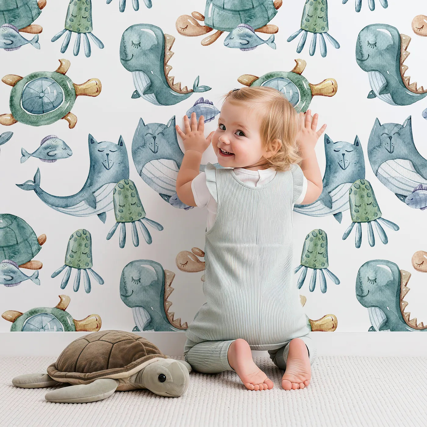 Lovely child standing in front of Whimsy Tots Ocean Pals Parade Wallpaper in White with whale, turtle, fish, octopus, jellyfish, sea dragon in design.