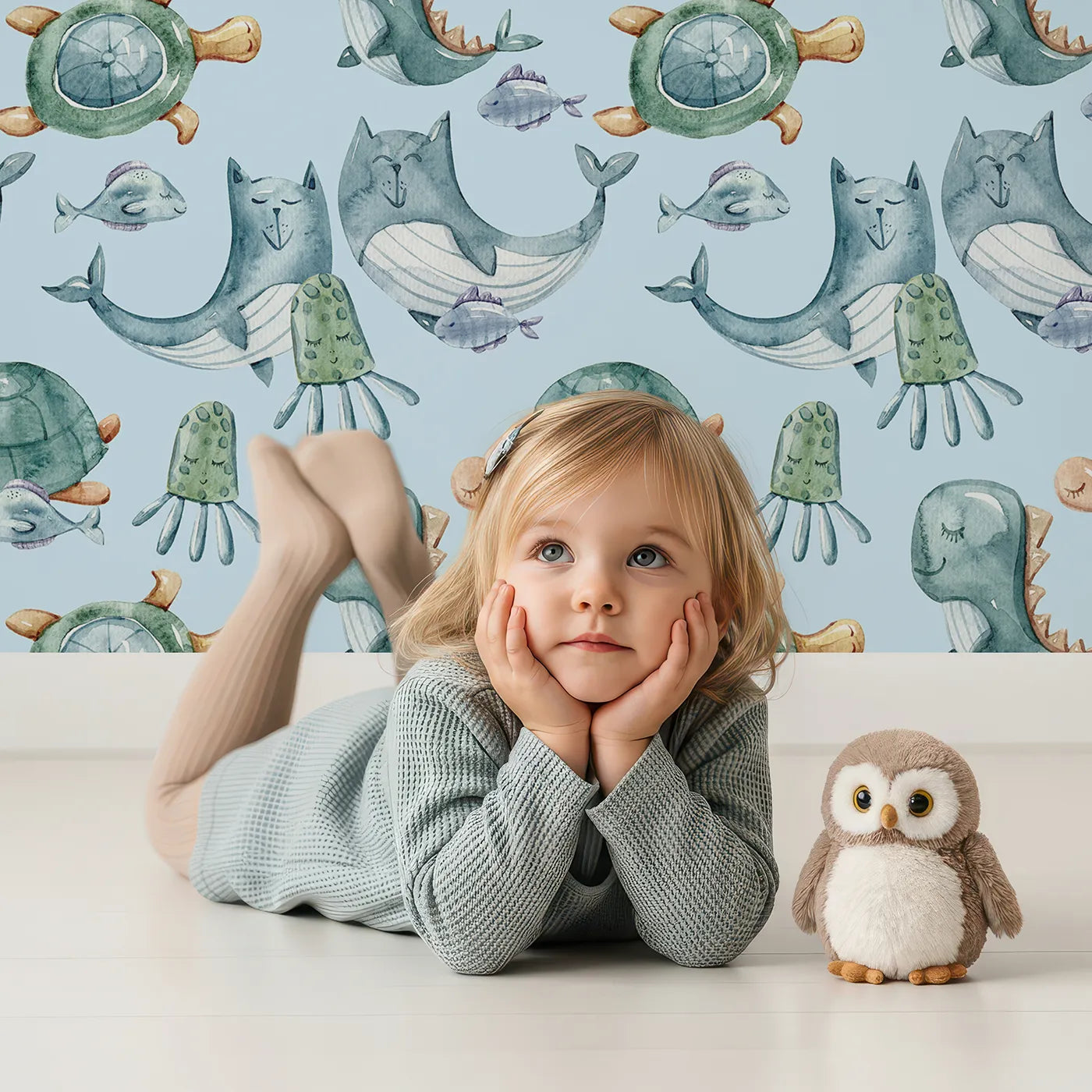 Lovely child standing in front of Whimsy Tots Ocean Pals Parade Wallpaper in Sky Blue with whale, turtle, fish, octopus, jellyfish, sea dragon in design.