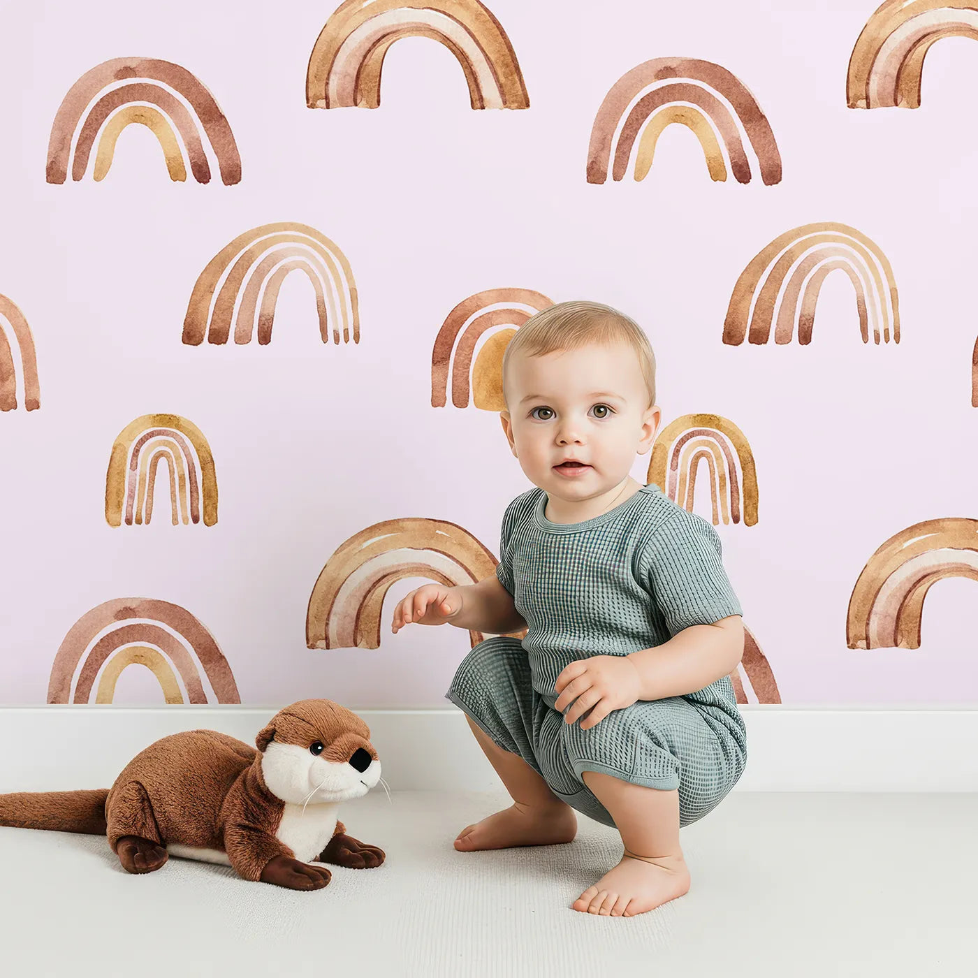 Lovely child standing in front of Whimsy Tots Boho Brush Rainbow Wallpaper in Pink with rainbow, stripe, arch in design.