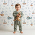 Lovely child standing in front of Whimsy Tots Seaside Vessel Parade Wallpaper in White with boat, submarine, splash, sail in design. Lovely child standing in front of Whimsy Tots Seaside Vessel Parade Wallpaper in White with boat, submarine, splash, sail in design.
