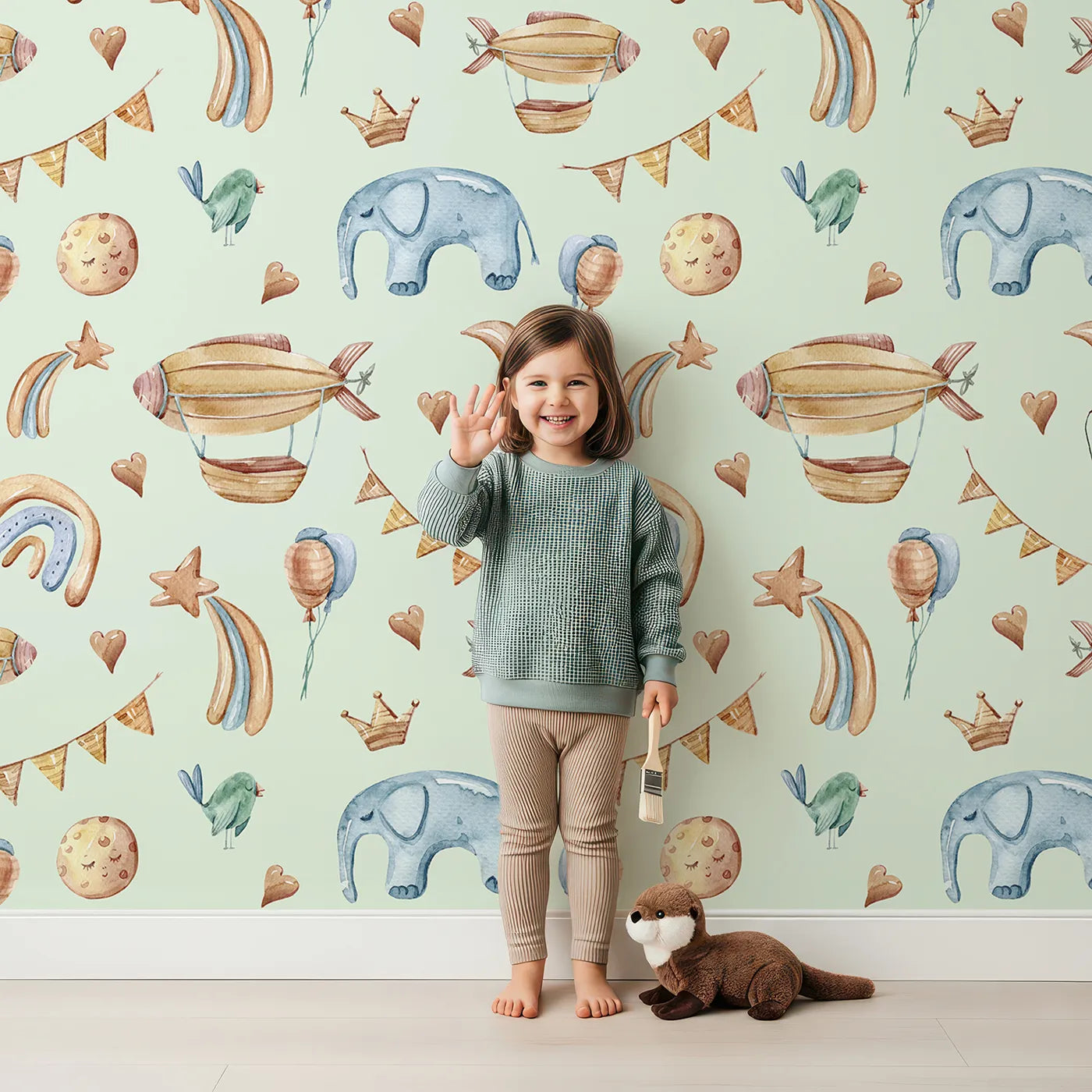 Lovely child standing in front of Whimsy Tots Sky Dreams Celebration Wallpaper in Mint Green with airship, balloon, crown, moon, rainbow, heart, elephant, bird in design.