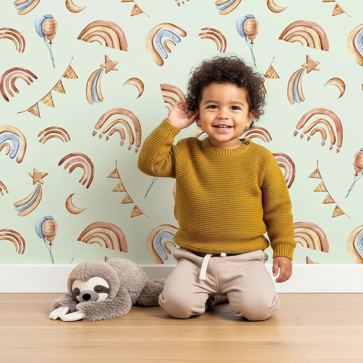 Lovely child standing in front of Whimsy Tots Sky Bloom Party Wallpaper in Mint Green with rainbow, balloon, moon, star, bunting, heart in design.