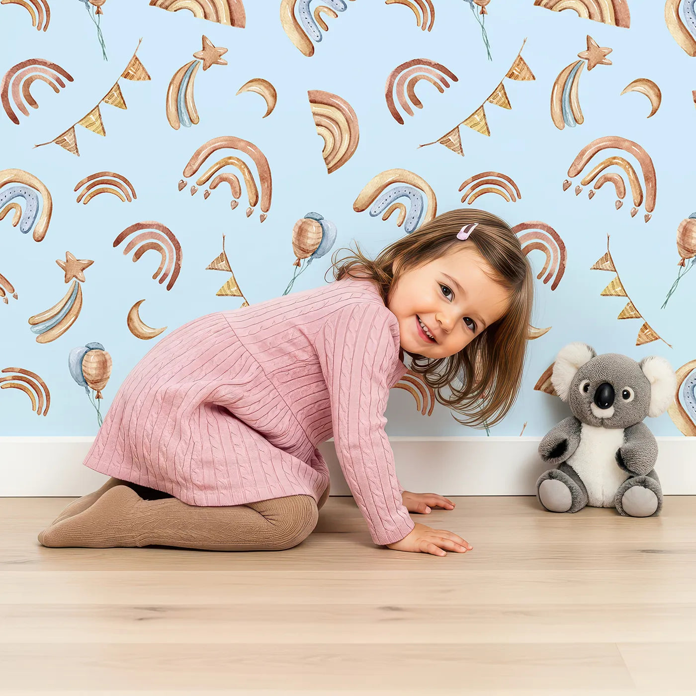 Lovely child standing in front of Whimsy Tots Sky Bloom Party Wallpaper in Blue with rainbow, balloon, moon, star, bunting, heart in design.