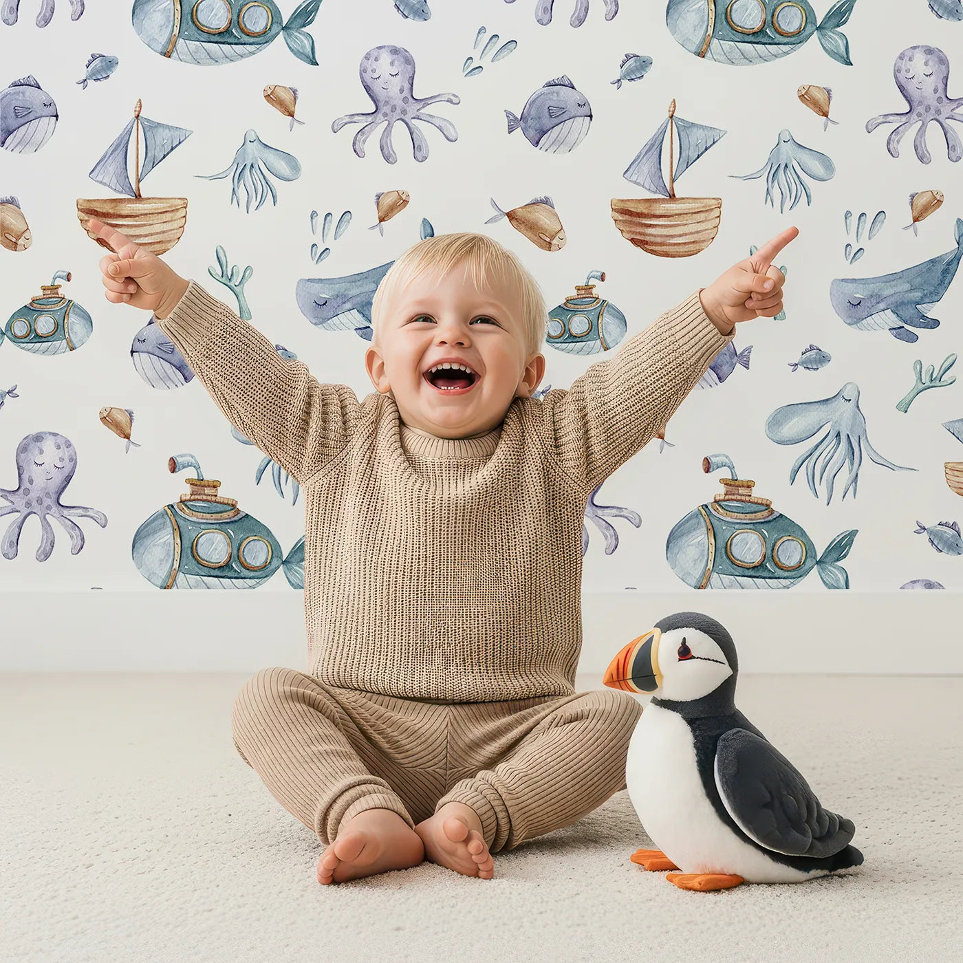 Lovely child standing in front of Whimsy Tots Deep Sea Discovery Wallpaper in White with whale, fish, submarine, jellyfish, seaweed, boat in design.