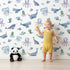 Lovely child standing in front of Whimsy Tots Whale Song Friends Wallpaper in White with whale, fish, narwhal, octopus, jellyfish in design. Lovely child standing in front of Whimsy Tots Whale Song Friends Wallpaper in White with whale, fish, narwhal, octopus, jellyfish in design.