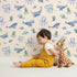 Lovely child standing in front of Whimsy Tots Whale Song Friends Wallpaper in Beige with whale, fish, narwhal, octopus, jellyfish in design. Lovely child standing in front of Whimsy Tots Whale Song Friends Wallpaper in Beige with whale, fish, narwhal, octopus, jellyfish in design.