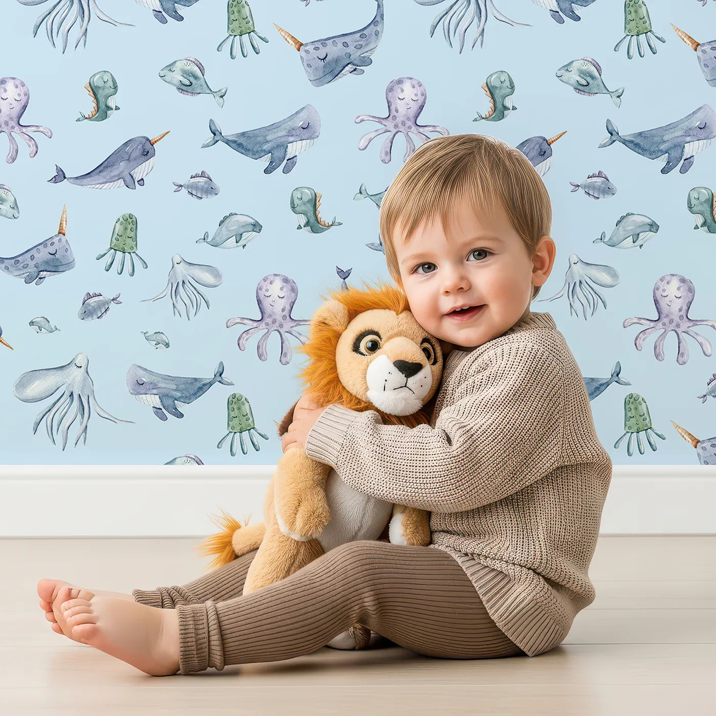 Lovely child standing in front of Whimsy Tots Whale Song Friends Wallpaper in Blue with whale, fish, narwhal, octopus, jellyfish in design.