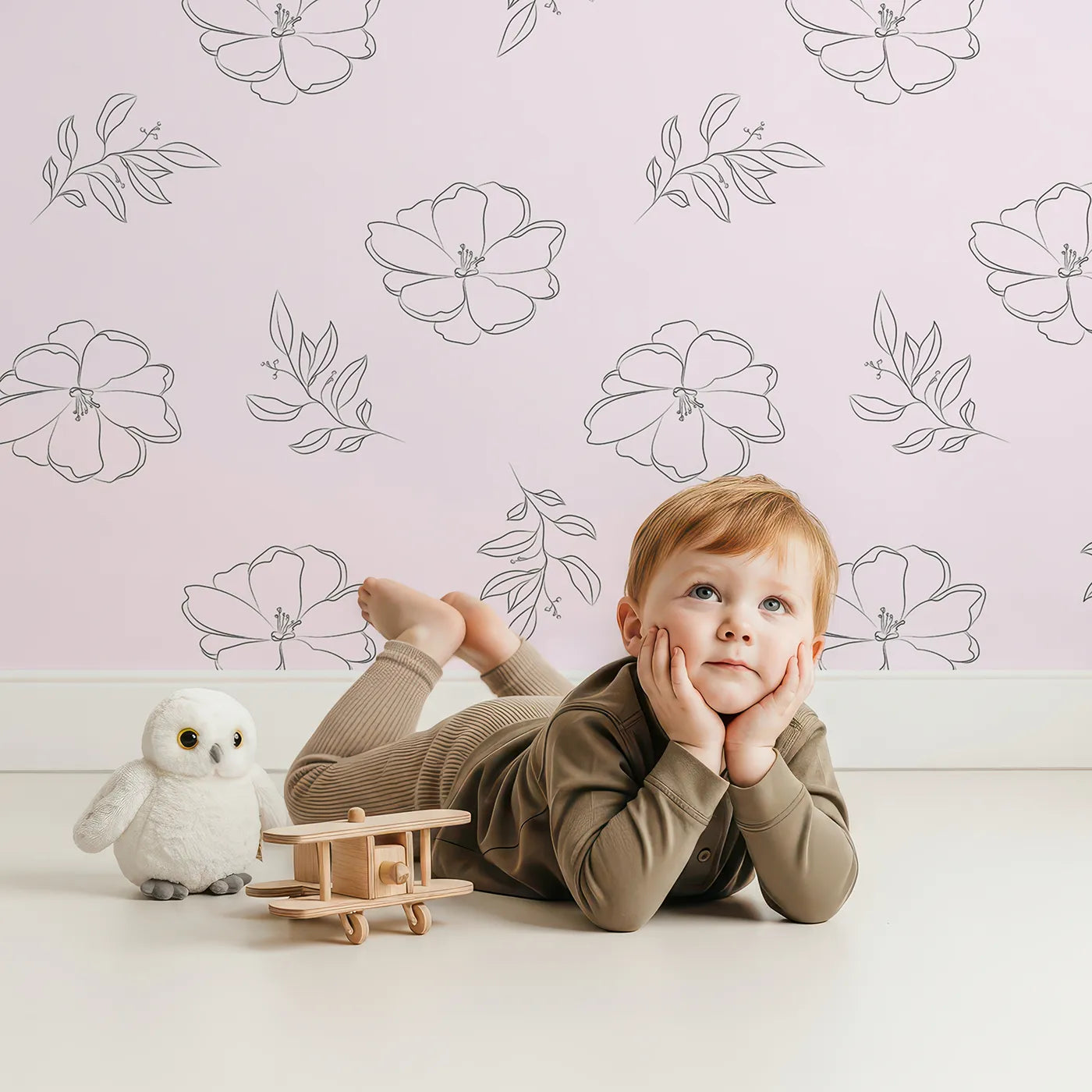 Lovely child standing in front of Whimsy Tots Petal Bloom Grace Wallpaper in Blush Pink with flower, leaf, blossom, sprig in design.