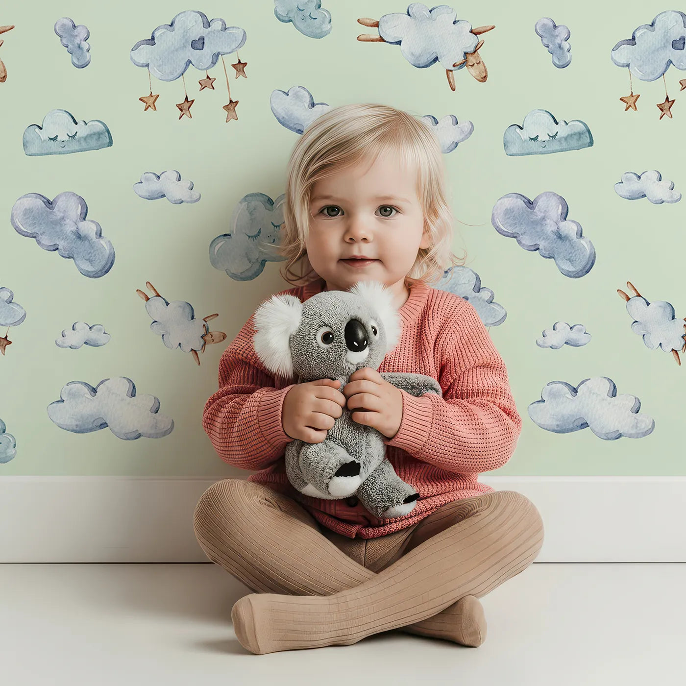 Lovely child standing in front of Whimsy Tots Cloudy Dreams Parade Wallpaper in Mint Green with cloud, star, sheep, sky in design.