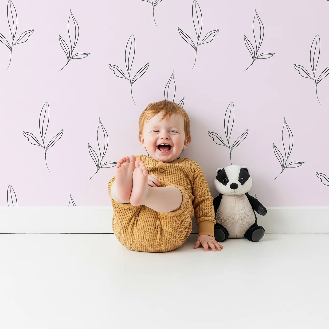 Lovely child standing in front of Whimsy Tots Whispering Leaflines Wallpaper in Blush Pink with leaf, sprig, botanical, line art in design.