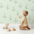 Lovely child standing in front of Whimsy Tots Whispering Leaflines Wallpaper in Mint Green with leaf, sprig, botanical, line art in design. Lovely child standing in front of Whimsy Tots Whispering Leaflines Wallpaper in Mint Green with leaf, sprig, botanical, line art in design.