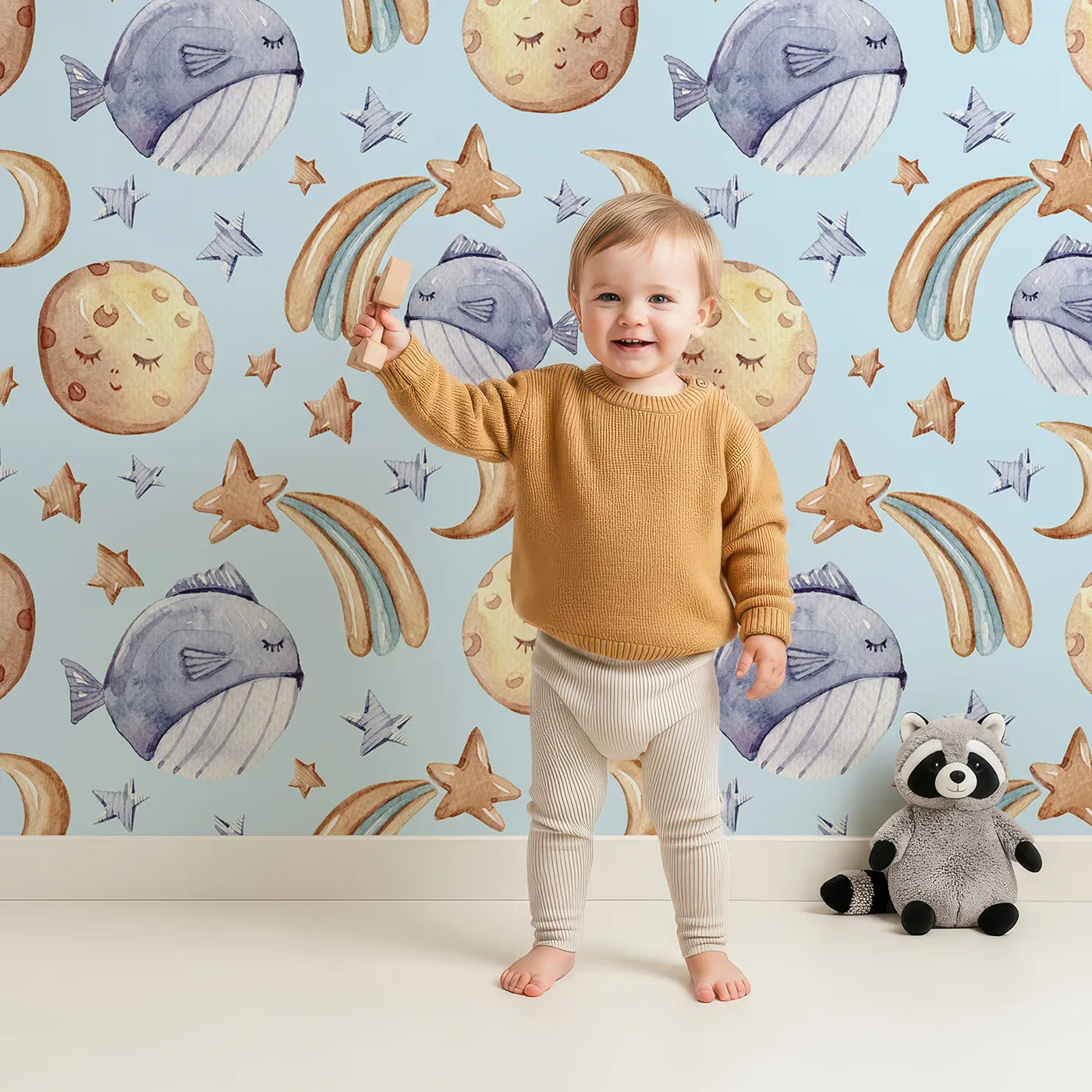 Lovely child standing in front of Whimsy Tots Sleepy Celestial Whale Wallpaper in Blue with whale, moon, star, fish, comet in design.