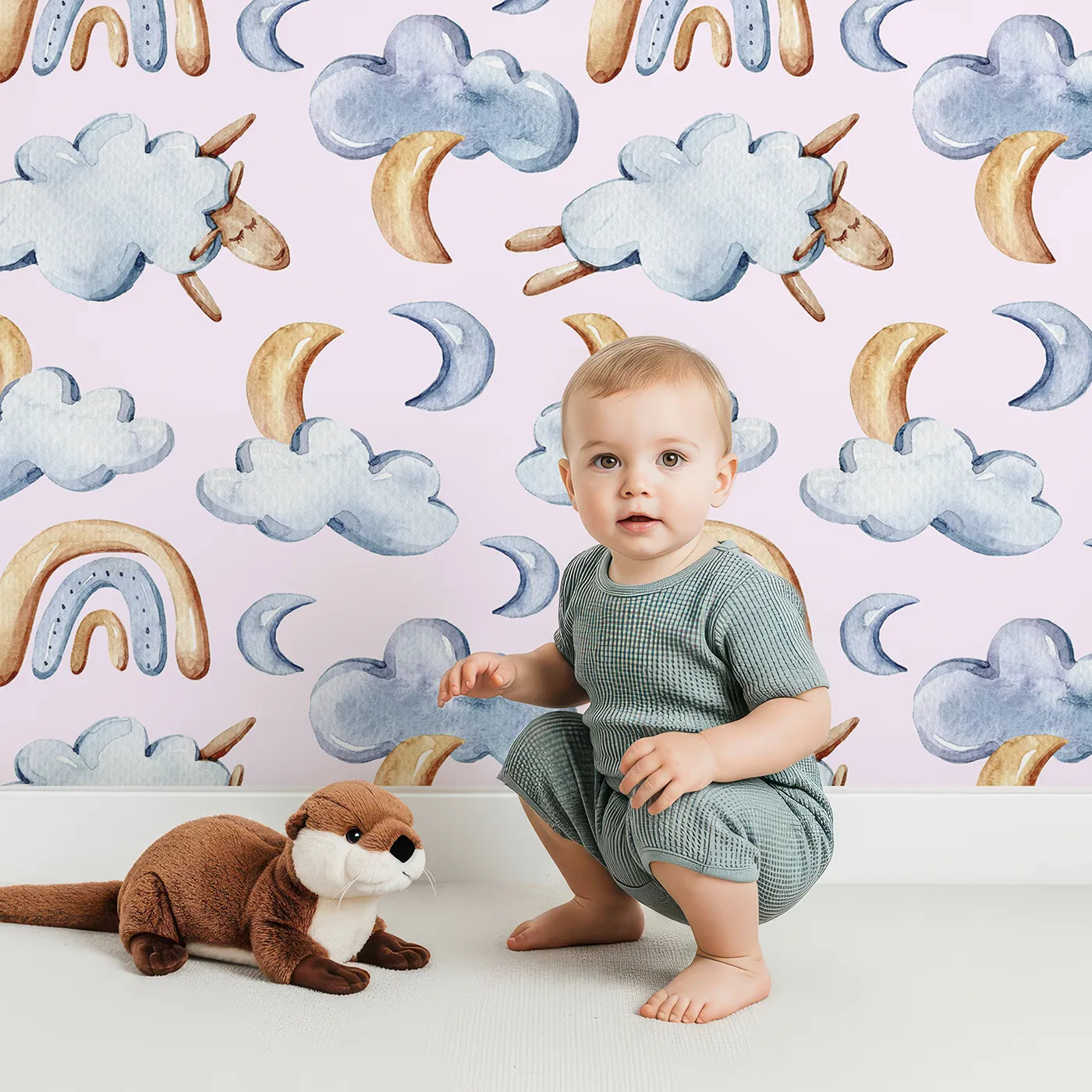 Lovely child standing in front of Whimsy Tots Sleepy Cloud Parade Wallpaper in Blush Pink with cloud, moon, sheep, rainbow, star in design.