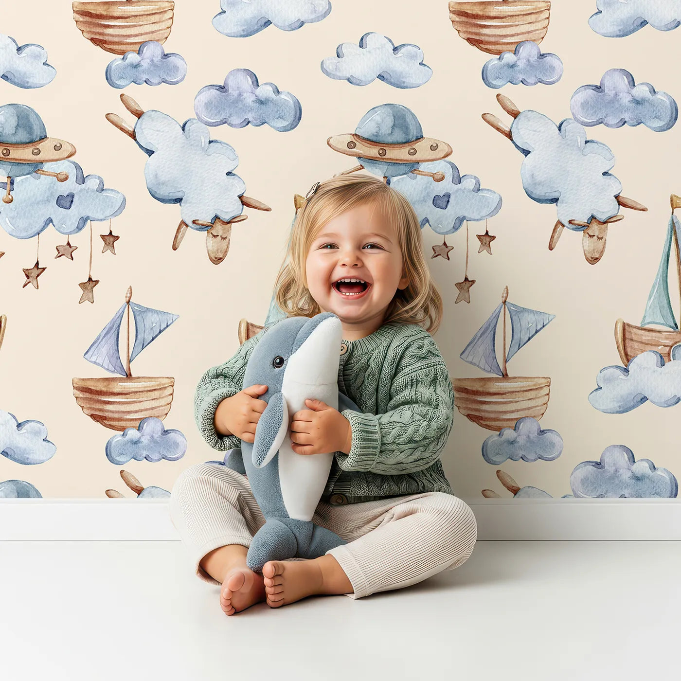 Lovely child standing in front of Whimsy Tots Counting Clouds and Sailing Dreams Wallpaper in Sand with sheep, boat, cloud, star, mobile in design.
