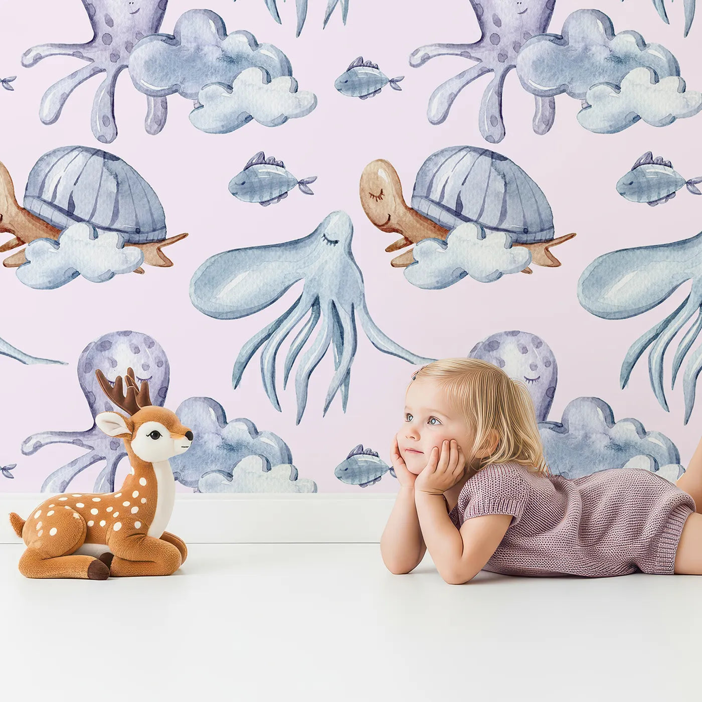Lovely child standing in front of Whimsy Tots Ocean Cloud Cuddle Wallpaper in Blush Pink with turtle, octopus, fish, cloud, squid in design.