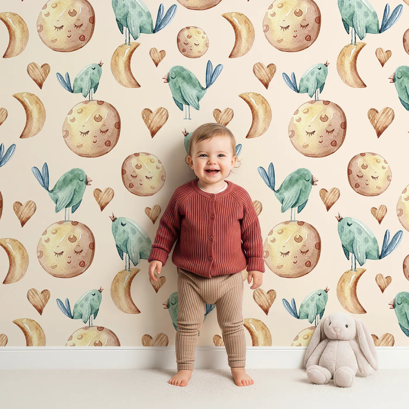 Lovely child standing in front of Whimsy Tots Lunar Lullaby Birds Wallpaper in Sand with bird, moon, heart in design.