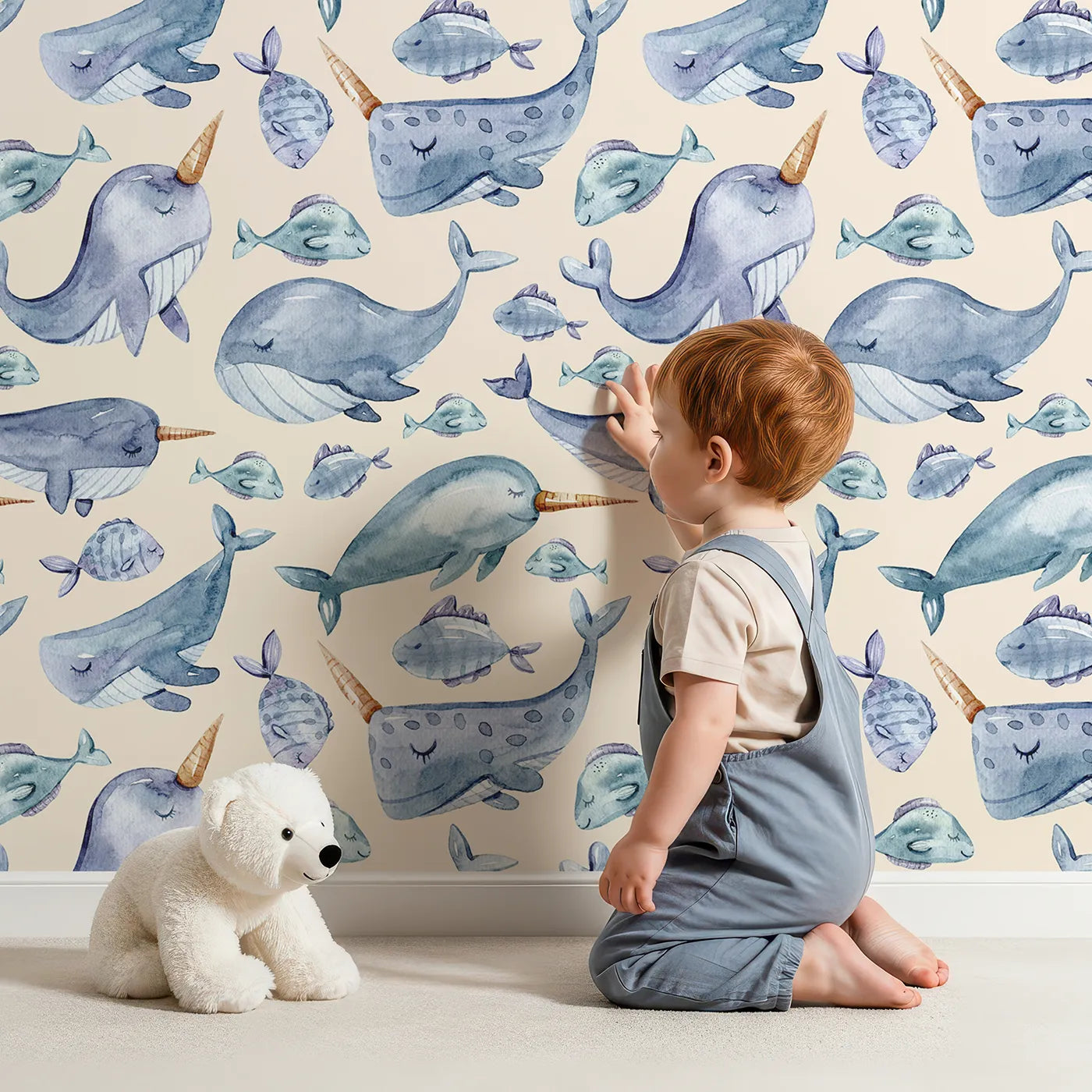 Lovely child standing in front of Whimsy Tots Sleepy Sea Friends Wallpaper in Sand with whale, narwhal, fish in design.