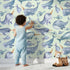 Lovely child standing in front of Whimsy Tots Sleepy Sea Friends Wallpaper in Mint Green with whale, narwhal, fish in design. Lovely child standing in front of Whimsy Tots Sleepy Sea Friends Wallpaper in Mint Green with whale, narwhal, fish in design.
