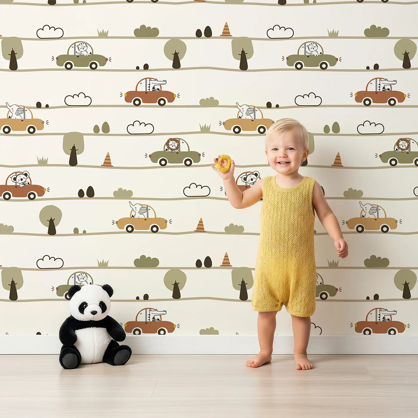 Lovely child standing in front of Whimsy Tots Zoomie Safari Drive Wallpaper with car, lion, elephant, koala, crocodile, tree, cloud, cone in design.