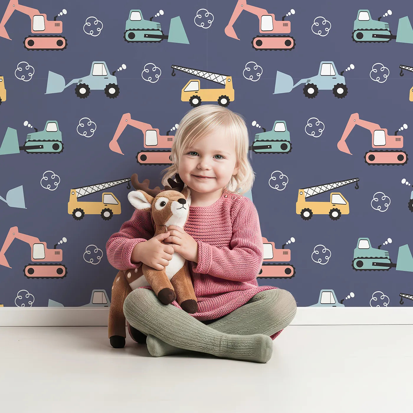 Lovely child standing in front of Whimsy Tots Mighty Machines Construction Wallpaper in Denim with truck, crane, bulldozer, excavator, vehicle in design.