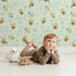 Lovely child standing in front of Whimsy Tots Busy Bees at Play Wallpaper in Mint Green with bee, flower, heart, honey in design. Lovely child standing in front of Whimsy Tots Busy Bees at Play Wallpaper in Mint Green with bee, flower, heart, honey in design.