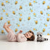 Lovely child standing in front of Whimsy Tots Busy Bees at Play Wallpaper in Sky with bee, flower, heart, honey in design. Lovely child standing in front of Whimsy Tots Busy Bees at Play Wallpaper in Sky with bee, flower, heart, honey in design.