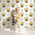 Lovely child standing in front of Whimsy Tots Bee Blossom Parade Wallpaper in White with bee, flower, honey in design. Lovely child standing in front of Whimsy Tots Bee Blossom Parade Wallpaper in White with bee, flower, honey in design.