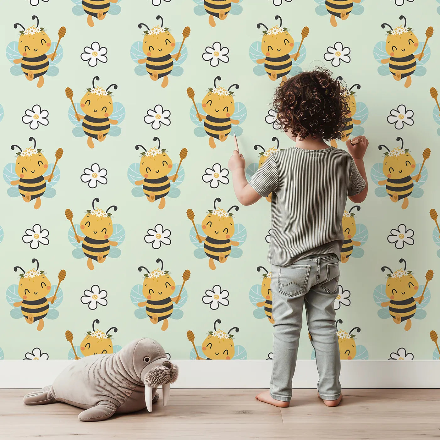 Lovely child standing in front of Whimsy Tots Bee Blossom Parade Wallpaper in Mint Green with bee, flower, honey in design.