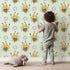 Lovely child standing in front of Whimsy Tots Bee Blossom Parade Wallpaper in Mint Green with bee, flower, honey in design. Lovely child standing in front of Whimsy Tots Bee Blossom Parade Wallpaper in Mint Green with bee, flower, honey in design.