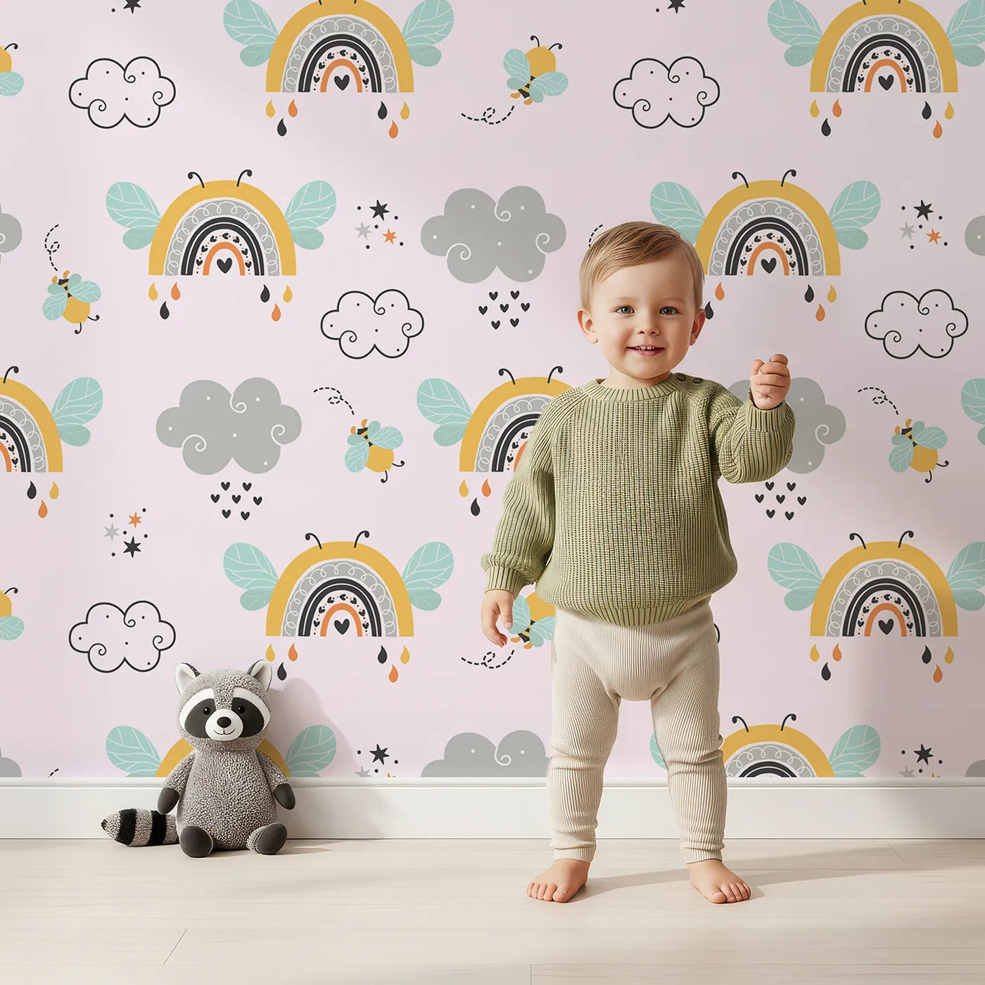 Lovely child standing in front of Whimsy Tots Bee Rainbow Dreams Wallpaper in Blush Pink with bee, rainbow, star, cloud in design.