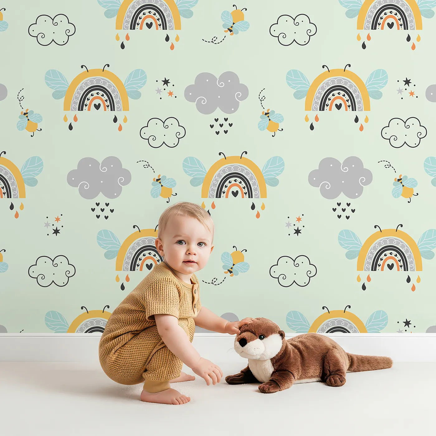 Lovely child standing in front of Whimsy Tots Bee Rainbow Dreams Wallpaper in Mint Green with bee, rainbow, star, cloud in design.