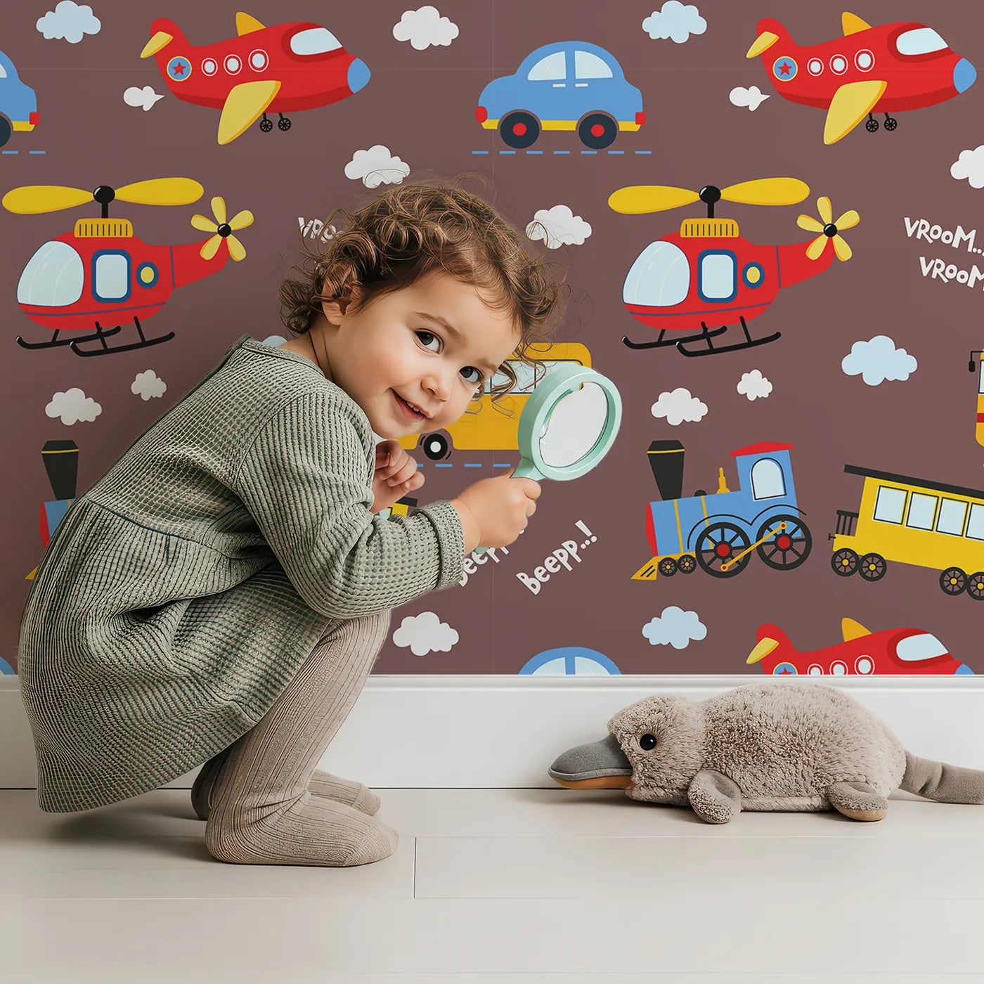 Lovely child standing in front of Whimsy Tots Vroom Vroom Transport Parade Wallpaper in Chocolate Brown with bus, train, plane, car, helicopter, cloud in design.