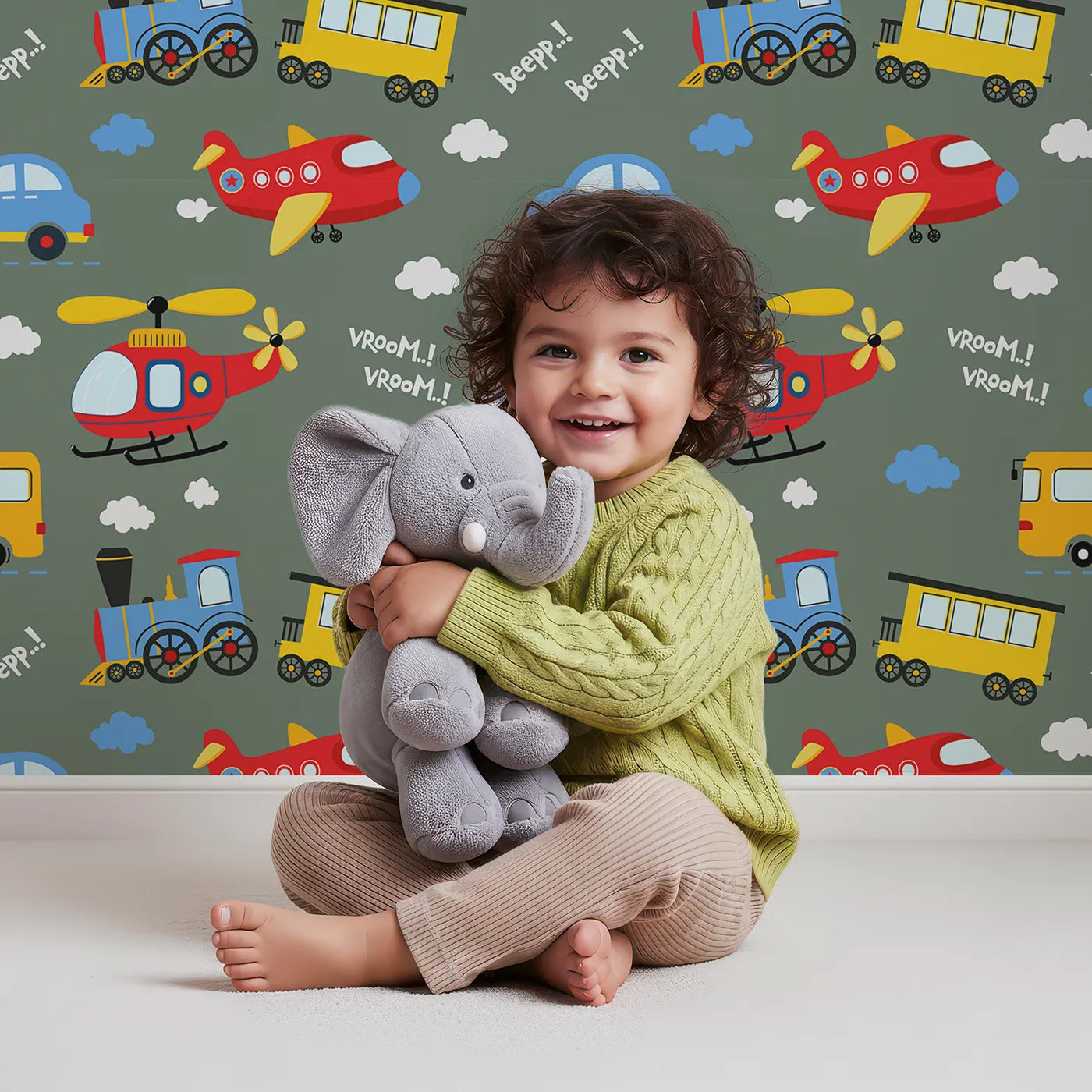 Lovely child standing in front of Whimsy Tots Vroom Vroom Transport Parade Wallpaper in Olive Green with bus, train, plane, car, helicopter, cloud in design.