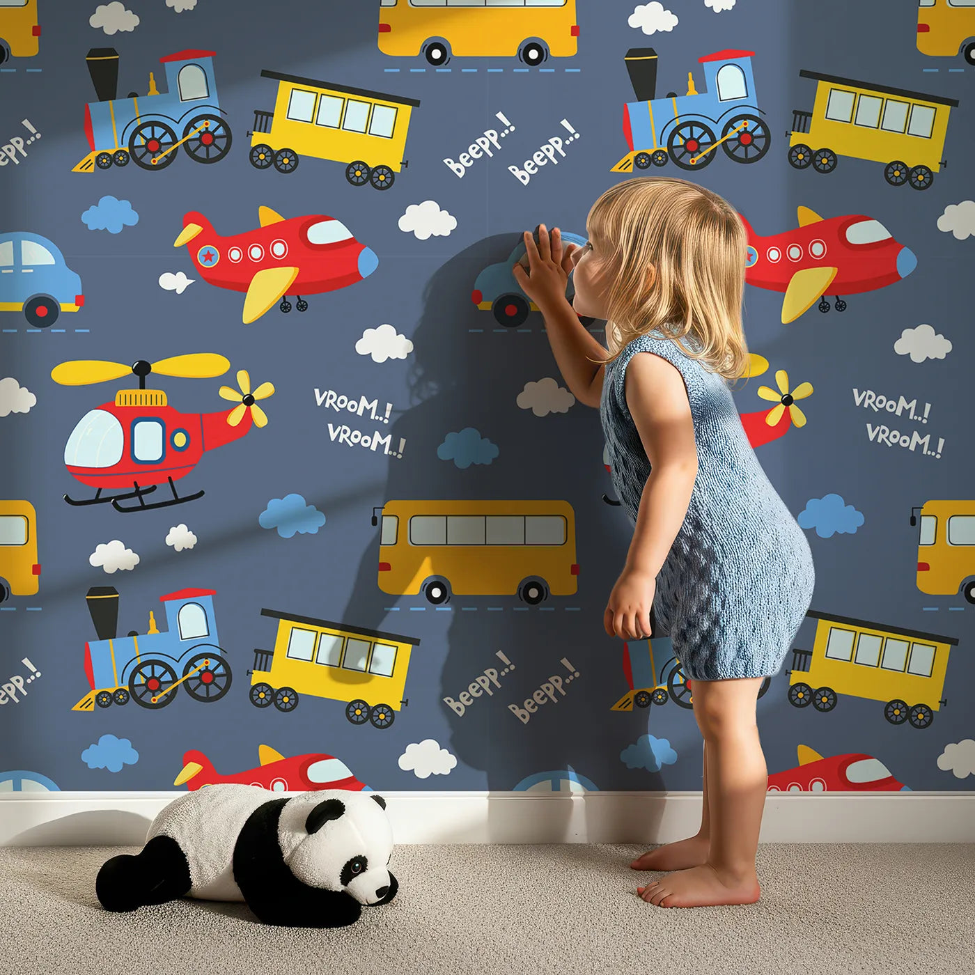 Lovely child standing in front of Whimsy Tots Vroom Vroom Transport Parade Wallpaper in Navy Blue with bus, train, plane, car, helicopter, cloud in design.