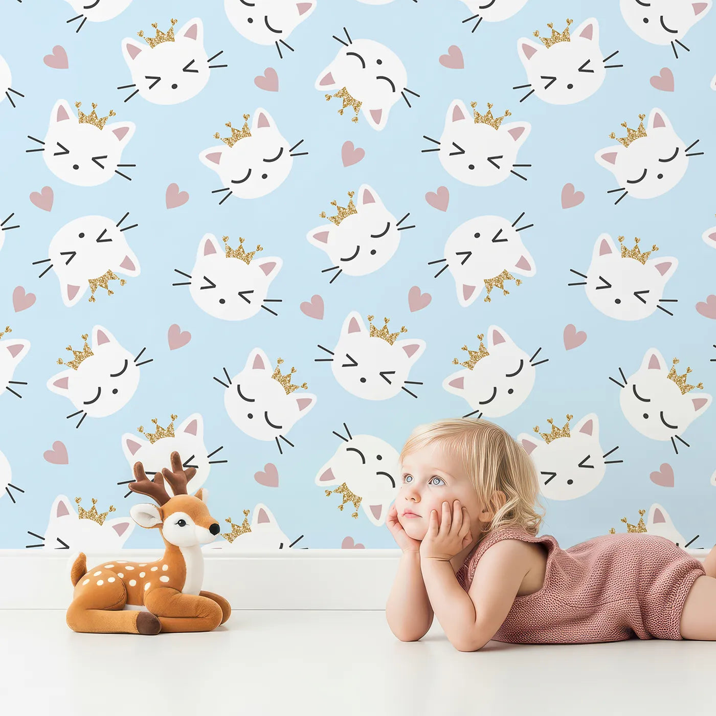 Lovely child standing in front of Whimsy Tots Royal Kitty Wink Wallpaper in Blue with cat, heart, crown in design.